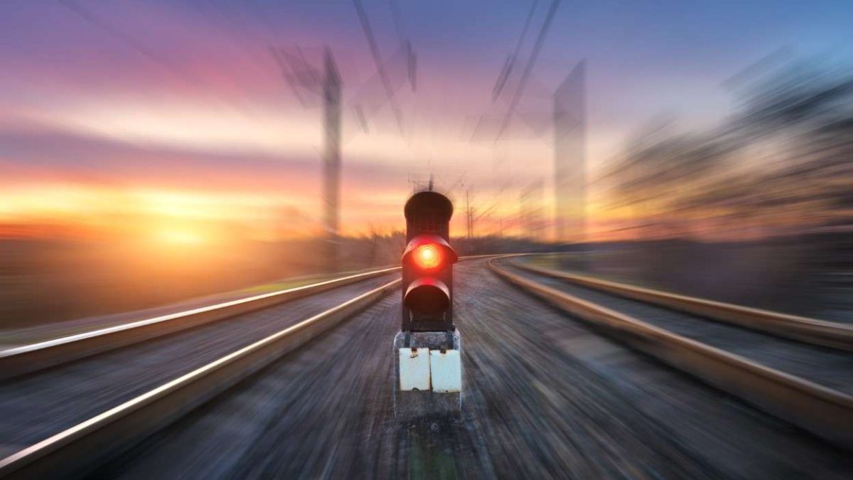Railway station and semaphore with motion blur effect against colorful sky with clouds at sunset. Concept industrial landscape. Railroad. Railway platform with traffic light. Heavy industry background